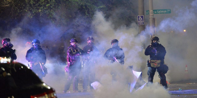 Security personnel stand in a cloud of tear gas in Portland, Oregon, early July 26, 2020. (Getty Images)