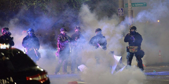 Security personnel stand in a cloud of tear gas in Portland, Oregon, early July 26, 2020. (Getty Images)