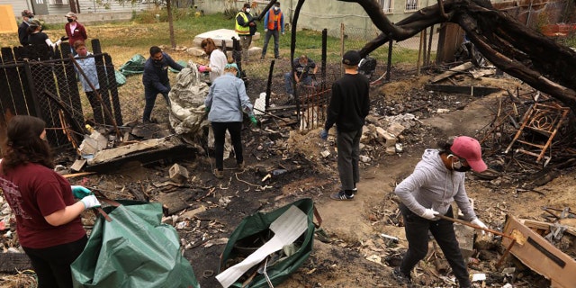 Residents living on a portion of 20th Street clean up debris that burned in a recent fire at a homeless encampment behind their homes in Los Angeles on April 24, 2021. (Genaro Molina / Los Angeles Times via Getty Images)