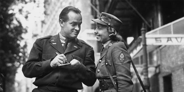 American comedian Bob Hope signing his autograph for a woman of the Motor Transport Corps outside the Savoy Theatre in London, before departing to Germany to entertain the troops.  Circa 1945.