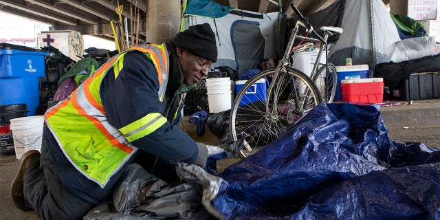 XL Jefferson Jr., 58, rolls up an extra tarp after repairing another person experiencing homelessness' tent on Feb. 13 in Austin, 텍사스. (Reuters/USA Today Network)