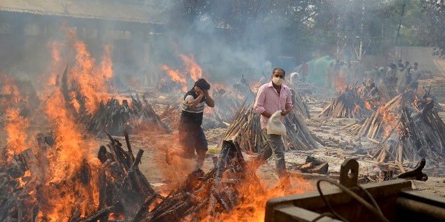 April 29, 2021: Relatives react to heat emitting from the multiple funeral pyres of COVID-19 victims at a crematorium in the outskirts of New Delhi, India. 