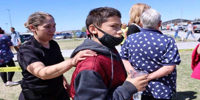 Adela Rodriguez, left, walks with her son, Yandel Rodriguez, 12, at the high school where people were evacuated after the shooting. (AP)