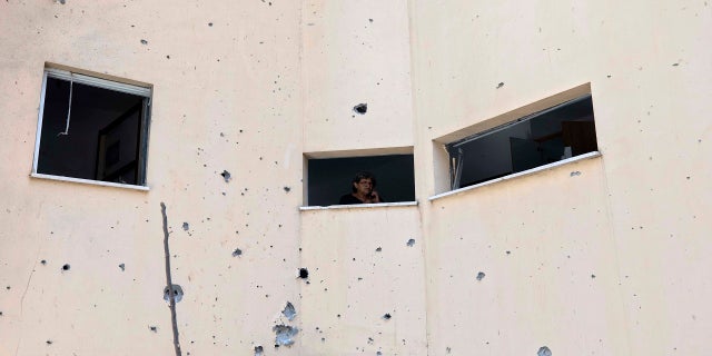 An Israeli woman looks out of her home window at the site of a rocket attack in the central Israeli town of Petah Tikvah on Thursday. (AP)
