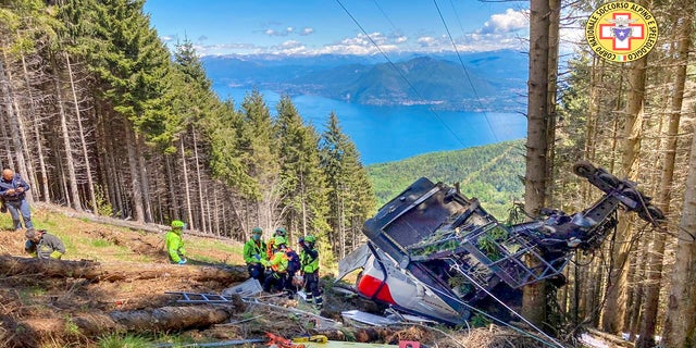 Rescuers work by the wreckage of a cable car after it collapsed near the summit of the Stresa-Mottarone line in the Piedmont region, northern Italy, on Sunday. 