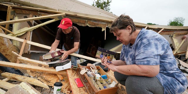 Vickie Savell, right, looks for her wedding band, as a friend and fellow church member pulls possessions from the remains of her new mobile home early Monday, May 3, 2021, in Yazoo County, Miss. Multiple tornadoes were reported across Mississippi on Sunday, causing some damage but no immediate word of injuries. (AP Photo/Rogelio V. Solis)