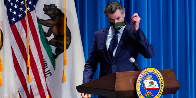 Le gouverneur de Californie Gavin Newsom enlève son masque facial lors d'une conférence de presse à Sacramento, en Californie. 
