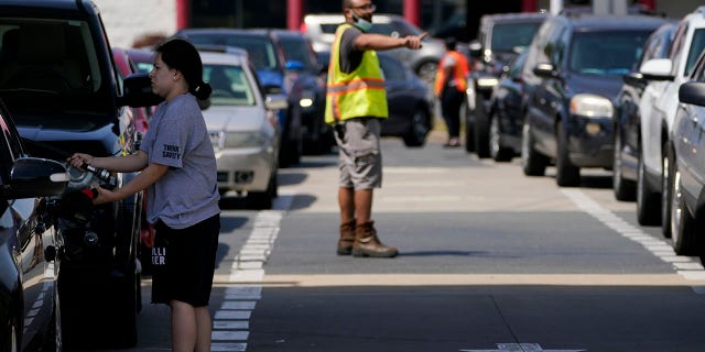 A customer pumps gas at Costco as a worker directs traffic on Tuesday in Charlotte, N.C. (AP)