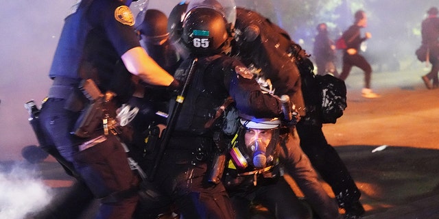 PORTLAND, OR - AGOSTO 14: Four Portland police officers arrest a protester during a crowd dispersal near Mississippi Avenue on August 14, 2020. 