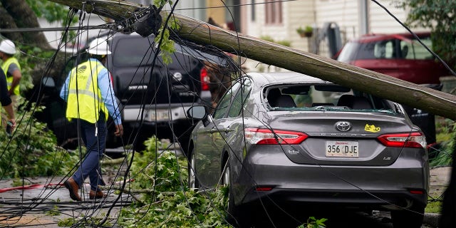 A downed power pole from a possible tornado sits on a damaged car after heavy storms moved through the area Tuesday night, in the Uptown section of New Orleans, Wednesday, May 12, 2021. (AP Photo/Gerald Herbert)
