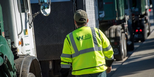 An employee walks toward a garbage collection truck in San Leandro, Calif., on Feb. 12, 2018. 