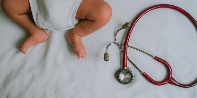 O bebê deitou-se e aguardou o exame de saúde com os estetoscópios para o exame de saúde do bebê. Conceito de verificação de saúde do bebê.