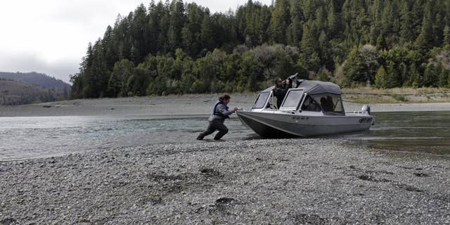 In this March 5, 2020, file photo, Hunter Maltz, a fish technician for the Yurok tribe, pushes a jet boat into the Klamath River at the confluence of the Klamath River and Blue Creek as Keith Parker, a Yurok tribal fisheries biologist, watches near Klamath, Calif. A severe drought is creating a water crisis not seen in more than a century for farmers, tribes and federally protected fish along the Oregon-California border as federal authorities cut off releases from a dam that provides critical sustenance for a massive irrigation project and bolsters downstream water levels for dangerously diminished salmon populations. (AP Photo/Gillian Flaccus, File)