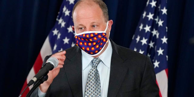 Colorado Gov. Jared Polis wears a face covering as he approaches the podium to make a point about the availability of COVID-19 vaccinations in the state during a news conference on the state's efforts against the coronavirus Tuesday, April 27, 2021, in Denver. (AP Photo/David Zalubowski)