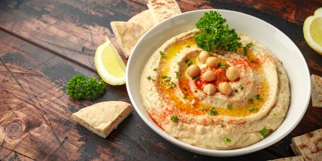 Hummus is made from cooked and mashed chickpeas. The dish is often mixed with olive oil, lemon, garlic and other seasonings. Many people serve hummus with chips, bread or vegetables. (iStock)