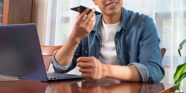 Young mexican latino man using laptop and smartphone (iStock)