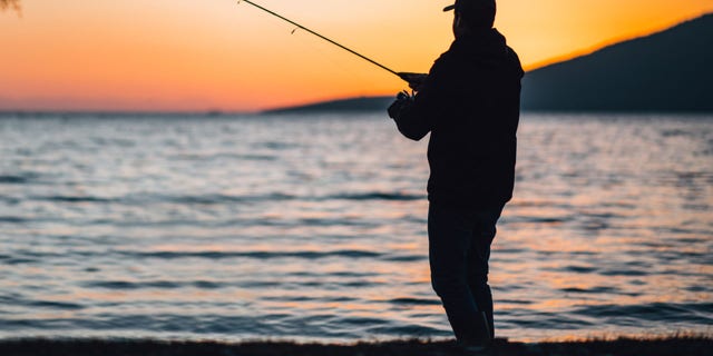 Young Man Fishing at the Beach at Sunset