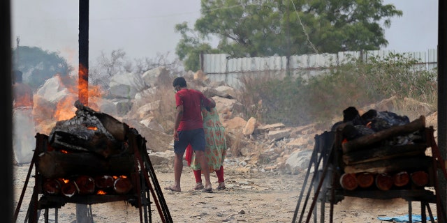 May 5, 2021: Family members of COVID-19 victims leave as their funeral pyres burn at an open crematorium set up at a granite quarry on the outskirts of Bengaluru, India.