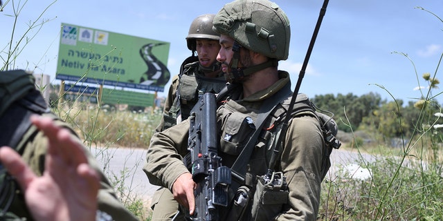 Israeli soldiers hold positions at Netiv HaAsara near the site where an IDF vehicle was directly hit by a rocket fired from Gaza Strip, injuring two and killing one May 12, 2021. 