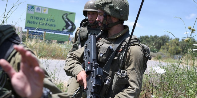 An Israeli soldier sits in Netiv HaAsara, near the scene where a rocket fired from the Gaza Strip hit an Israel Defense Forces vehicle, injuring two and killing one on May 12, 2021. 