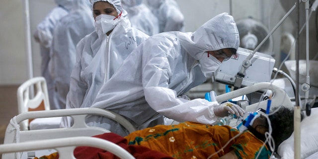 May 6, 2021: A medical staff attempts to adjust a patient's oxygen mask in the BKC large field hospital, one of the largest COVID-19 facilities in India.