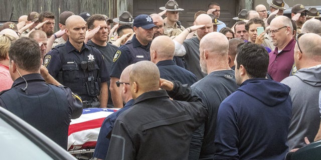 Officers line the path four deep as the body of a slain Champaign, Ill., police officer Christopher Oberheim is taken into the coroner's office, Wednesday, May 19, 2021, in Urbana, Ill.