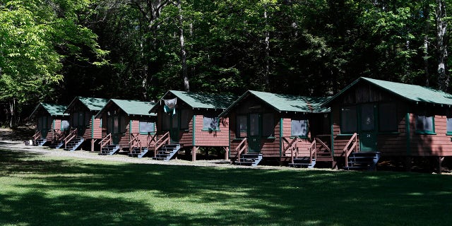 FILE - This Thursday, June 4, 2020 file photo shows a row of cabins at a summer camp in Fayette, Maine. On Friday, May 28, 2021, the Centers for Disease Control and Prevention posted guidance saying kids at summer camps can skip wearing masks outdoors, with some exceptions. Children who aren’t fully vaccinated should still wear masks outside when they’re in crowds or in sustained close contact with others – and when they are inside, and fully vaccinated kids need not wear masks indoors or outside, the CDC says. (AP Photo/Robert F. Bukaty, File)