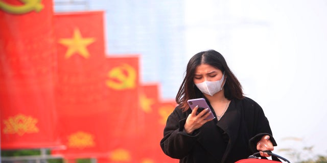 A woman wearing face mask looks at her phone in Hanoi, Vietnam.  (AP Photo/Hau Dinh, File)