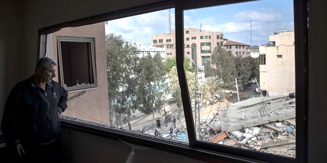 A Palestinian man looks from a broken window at the remains of a six-story building destroyed by an early morning Israeli airstrike, in Gaza City, Tuesday, May 18, 2021. (Associated Press)