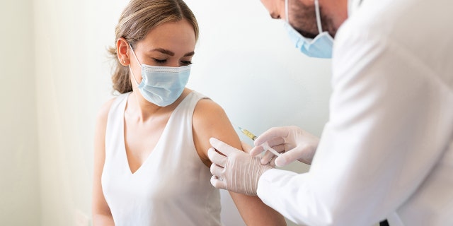 Woman in a doctor's office about to receive a vaccine. 