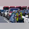 A customer helps pump gas at Costco, as others wait in line, on Tuesday, May 11, 2021, in Charlotte, North Carolina. Colonial Pipeline, which delivers about 45% of the fuel consumed on the East Coast, halted operations last week after revealing a cyberattack that it said had affected some of its systems.