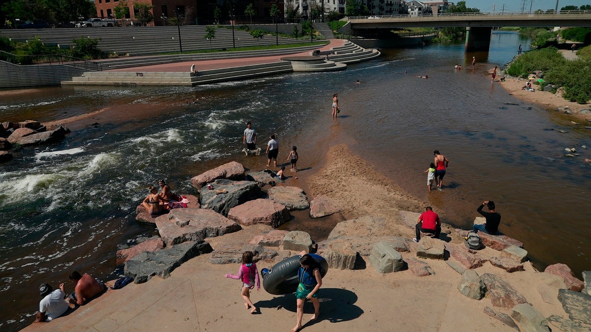 People cool off in the water at the confluence of the South Platte River and Cherry Creek in Denver, Colorado on June 14, 2021. By mid-afternoon, the temperature hit 96 degrees as part of the heat wave sweeping across the western U.S. (AP Photo/Brittany Peterson)