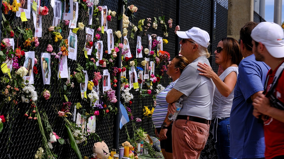 People mourn at the memorial site created by neighbors in front of the partially collapsed building where the rescue personnel continue their search for victims, in Surfside near Miami Beach, Fla., June 26, 2021. (REUTERS/Maria Alejandra Cardona)