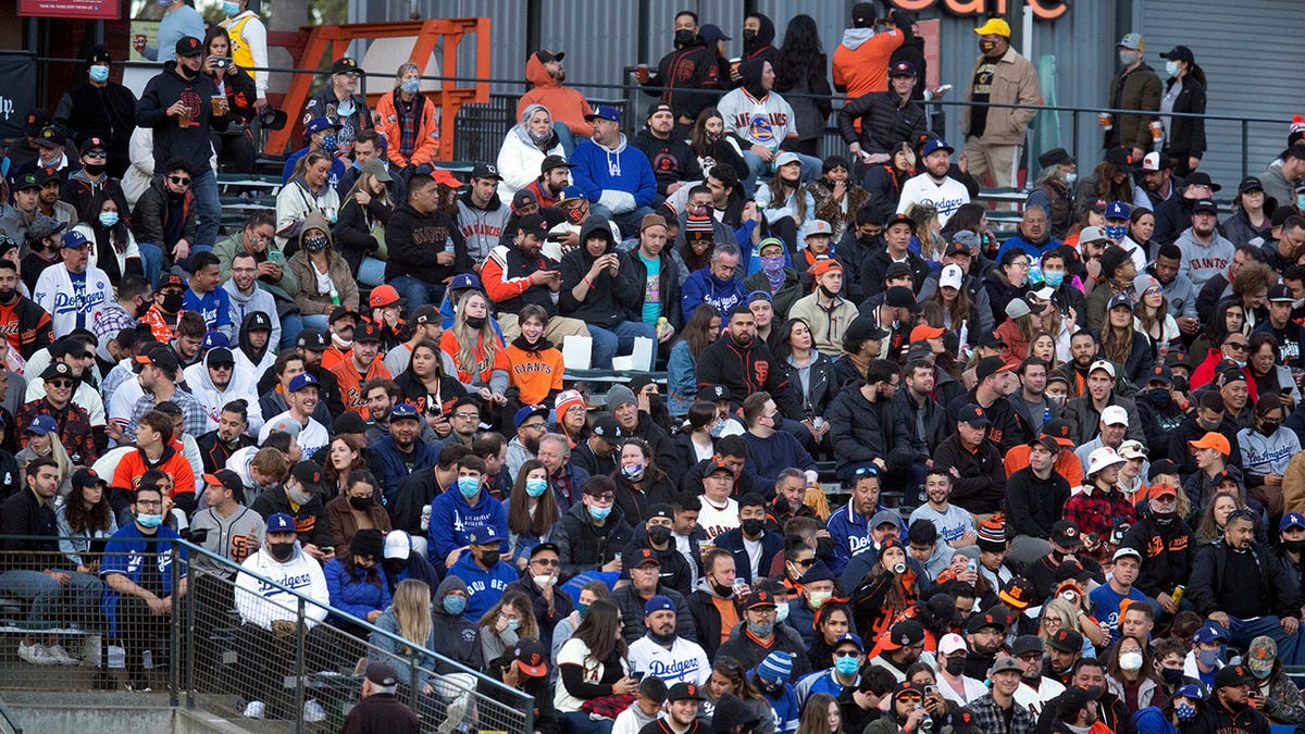 In this May 21, 2021, file photo, fans sit shoulder to shoulder in a vaccinated section of the stands during the fourth inning of a baseball game between the Los Angeles Dodgers and San Francisco Giants in San Francisco. California, the first state in America to put in place a coronavirus lockdown, is now turning a page on the pandemic. (Credit: AP Photo/D. Ross Cameron)