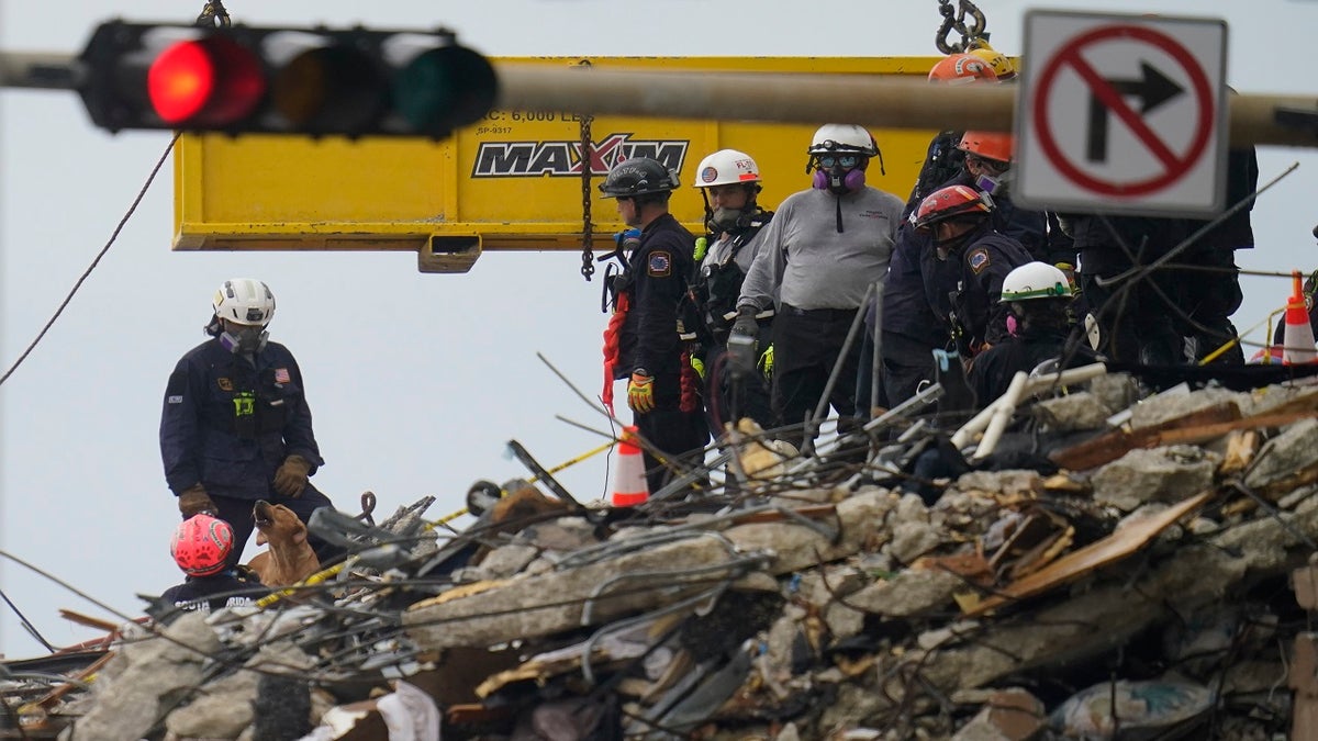 A dog working with search and rescue personnel barks to alert them after sniffing a spot atop the rubble at the Champlain Towers South condo building on Wednesday. (AP)