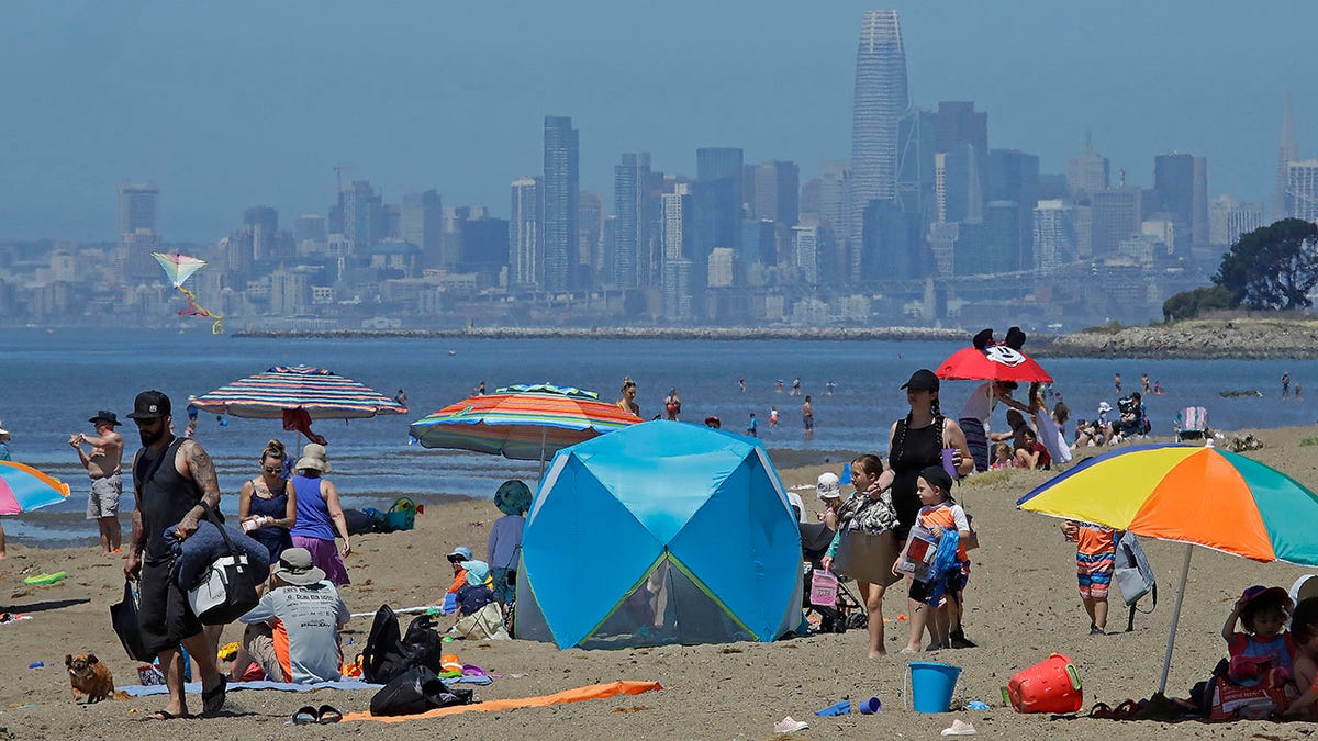 In this May 26, 2020, file photo, people congregate on Robert W. Crown Memorial State Beach with the San Francisco skyline as a backdrop in Alameda, Calif. Officials are urging residents to stay hydrated and find shade as temperatures soar across much of central and northern California. Over 9 million people are under a heat advisory or excessive heat warning. With the soaring temperatures comes an increased risk of wildfires in the state where vegetation is extremely dry after a winter and spring with relatively little rain and snow. California's power grid operator says it's not anticipating outages during the heat wave. (AP Photo/Ben Margot, File)