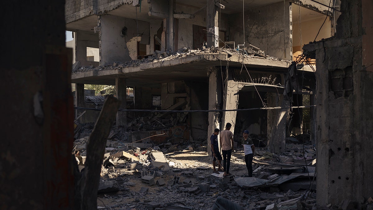 Palestinians stand among the rubble of a building that collapsed after it was hit by airstrikes during an 11-day war between Gaza's Hamas rulers and Israel, in Maghazi, Gaza Strip, Wednesday, June 2, 2021. (AP Photo/Felipe Dana)