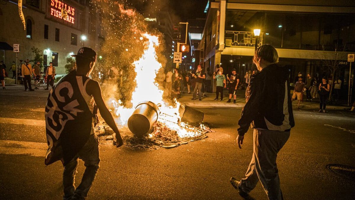 Protesters set a dumpster on fire after a shooting on Thursday, June 3, 2021 in Minneapolis. Crowds vandalized buildings and stole from businesses in Minneapolis’ Uptown neighborhood after officials said a man wanted for illegally possessing a gun was fatally shot by authorities. (Richard.Tsong-Taatari/Star Tribune via AP)