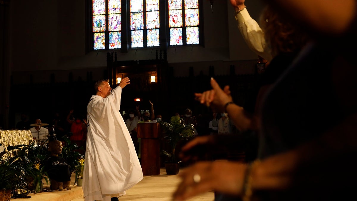 Parishioners raise their hands as Rev. Michael Pfleger conducts his first Sunday church service as a senior pastor at St. Sabina Catholic Church following his reinstatement by Archdiocese of Chicago after decades-old sexual abuse allegations against minors, Sunday, June 6, 2021, in the Auburn Gresham neighborhood in Chicago. (AP Photo/Shafkat Anowar)