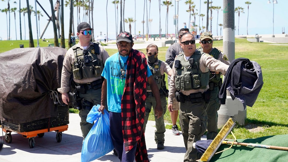 Members of the Los Angeles County Sheriff's Department's HOST, Homeless Outreach Service Team, walk with a homeless man on Tuesday in the Venice Beach section of Los Angeles. (AP Photo/Marcio Jose Sanchez)
