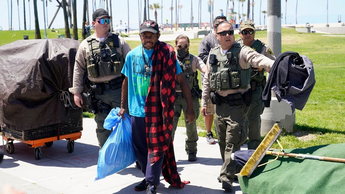 Members of the Los Angeles County Sheriffs Department's HOST, Homeless Outreach Service Team, walk with a homeless man in Venice Beach. (AP Photo/Marcio Jose Sanchez)