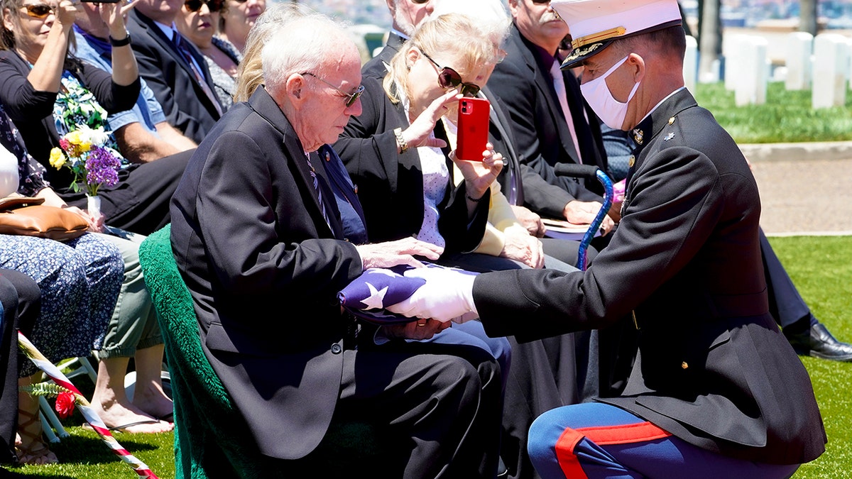 Lt. Col. Christopher Benson, right, presents the flag that covered U.S. Marine Corps, Pfc. John Franklin Middleswart casket, to his nephew Edward Brown during the full military honors ceremony at Fort Rosecrans National Cemetery Tuesday, June 8, 2021, in San Diego. Middleswart was 19 when he was killed along with more than 400 other Marines and Navy sailors aboard the battleship Oklahoma in a surprise attack by the Japanese that led the U.S. into World War II. (Nelvin C. Cepeda/The San Diego Union-Tribune via AP)