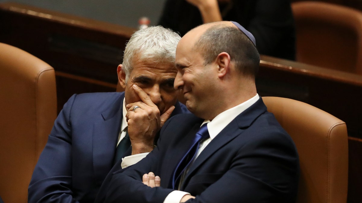 Israel's new prime minister, Naftali Bennett, sits with Yair Lapid, left, during a Knesset session in Jerusalem Sunday, June 13, 2021. Israel's parliament has voted in favor of a new coalition government, formally ending Prime Minister Benjamin Netanyahu's historic 12-year rule. (AP Photo/Ariel Schalit)