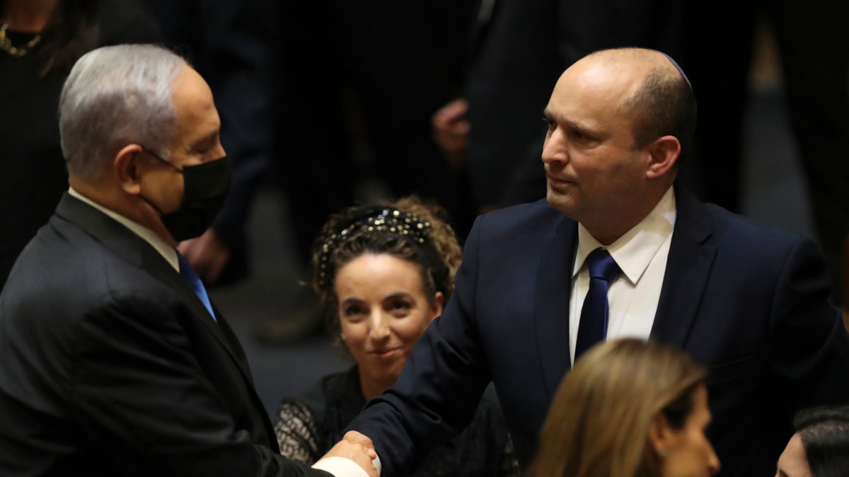 Israel's new prime minister, Naftali Bennett, shakes hands with outgoing prime minister Benjamin Netanyahu during a Knesset session in Jerusalem Sunday, June 13, 2021. Israel's parliament has voted in favor of a new coalition government, formally ending Netanyahu's historic 12-year rule. (AP Photo/Ariel Schalit)