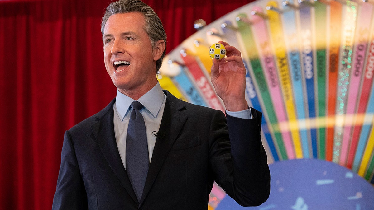 FILE - In this June 4, 2021, file photo, California Gov. Gavin Newsom holds up a lottery ball at the California Lottery Headquarters on Friday, June 4, 2021, in Sacramento, Calif., while drawing numbers for California's new vaccine incentive program. California, the first state in America to put in place a coronavirus lockdown, is now turning a page on the pandemic. Most of California's coronavirus restrictions will disappear Tuesday, June 15, 2021.
