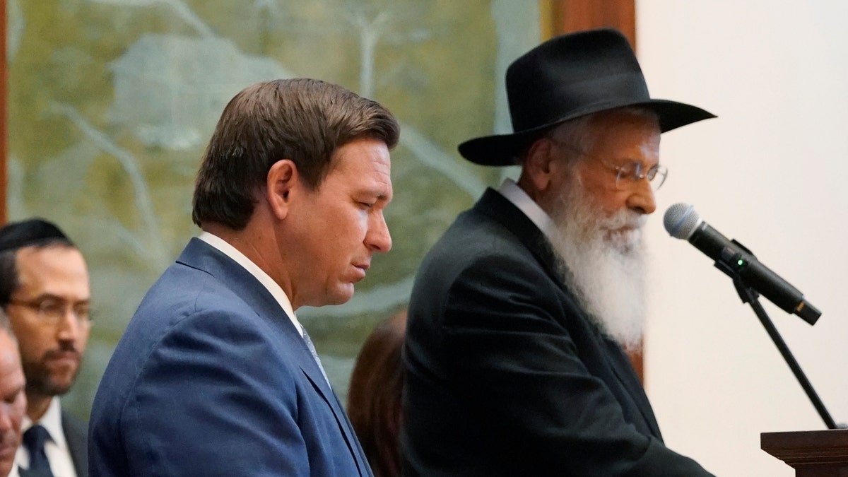 Florida Gov. Ron DeSantis, left, and Rabbi Sholom Lipskar participate in a moment of silence, Monday, June 14, 2021, at the Shul of Bal Harbour, a Jewish community center in Surfside, Fla. (AP Photo/Wilfredo Lee)