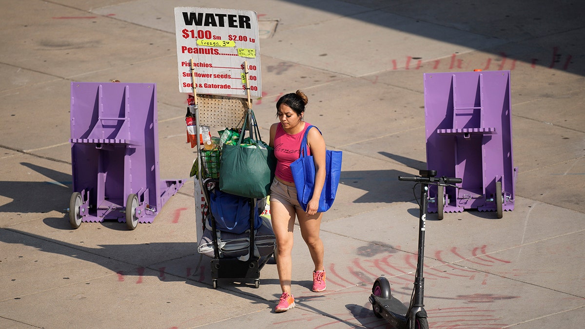 As temperatures soar above triple digits, a vendor pulls a wagon filled with water outside Coors Field during afternoon rush hour Tuesday, June 15, 2021, in Denver. (AP Photo/David Zalubowski)
