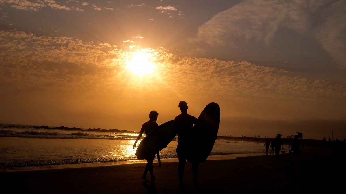 Surfers are silhouetted as they leave the water during the sun set on Wednesday, June 16, 2021, in the Venice Beach section of Los Angeles. An unusually early and long-lasting heat wave brought more triple-digit temperatures Wednesday to a large swath of the U.S. West, raising concerns that such extreme weather could become the new normal amid a decades-long drought.(AP Photo/Ringo H.W. Chiu)
