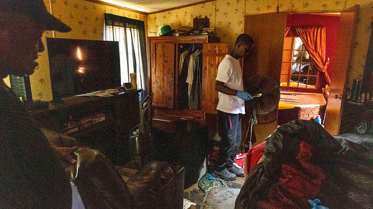 Percy Ross, left, the owner, watches his son, Michael Roberts, search Ross's flood-damaged home Sunday, June 20, 2021, after the heavy flooding Saturday in Northport, Ala. (AP Photo/Vasha Hunt)