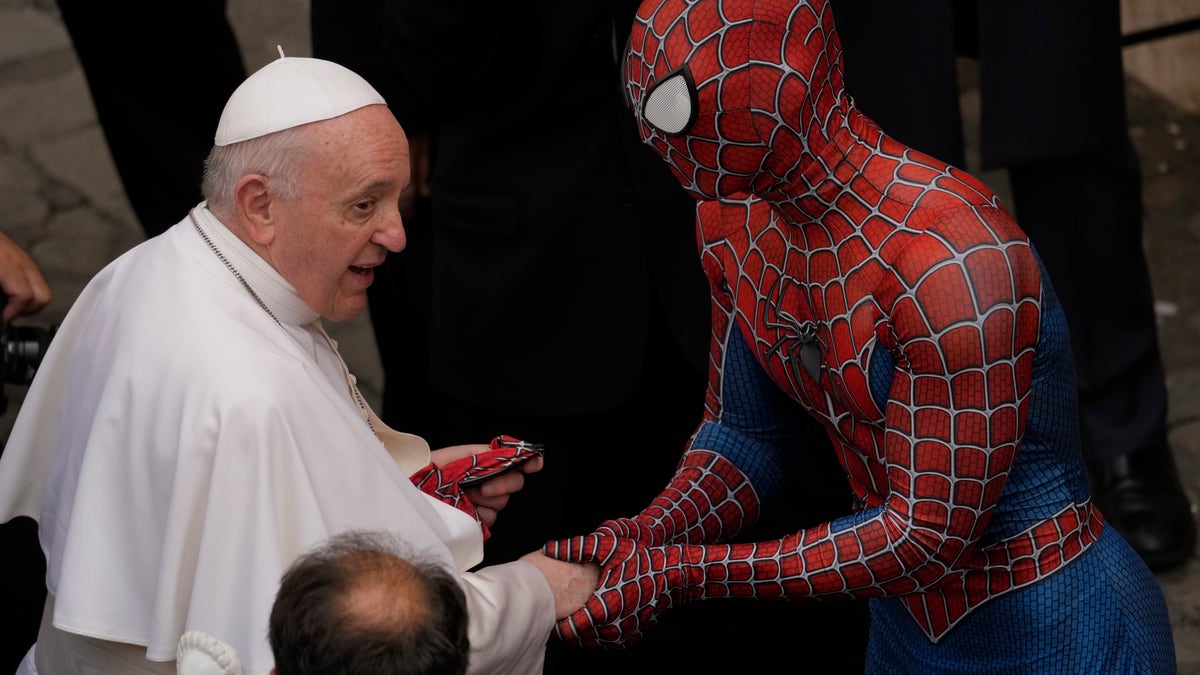 Pope Francis meets Spider-Man, who presents him with his mask, at the end of his weekly general audience with a limited number of faithful in the San Damaso Courtyard at the Vatican, Wednesday, June 23, 2021. The masked man works with sick children in hospitals. (AP Photo/Andrew Medichini)